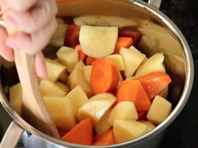 預備大鍋落油中火燒熱，加入薯仔和胡蘿蔔炒香。