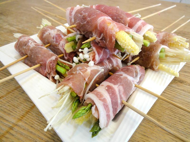 1片的猪梅花肉片铺平,放上3根芦笋,2条玉米笋和少许金针菇,轻轻的卷起